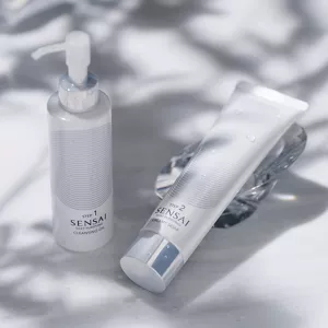 I flaconi di Silky Purifying Cleansing Oil e di Creamy Soap sono accostati su una superficie bianca